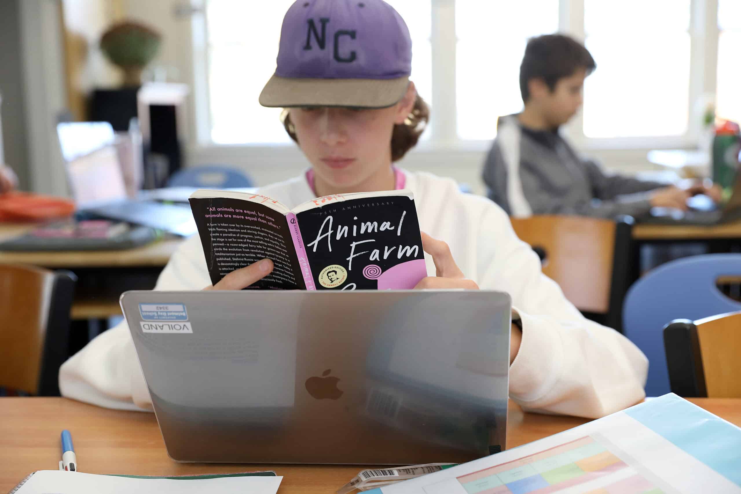 A student reads Animal Farm at his desk