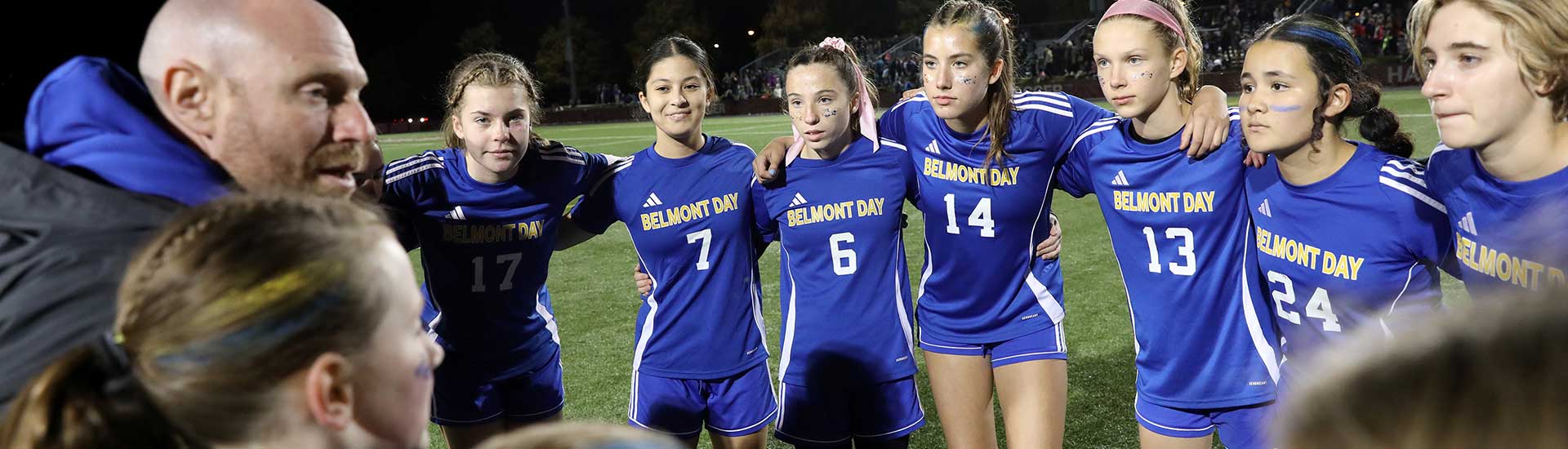 Coach Marks and the girls' soccer team huddle before a game